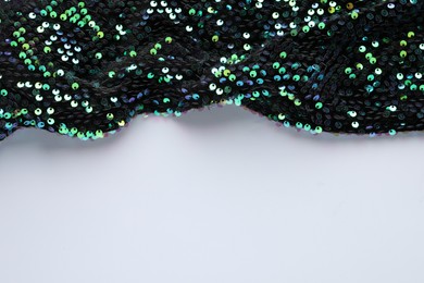 Photo of Dark shiny sequin fabric on white background, above view. Space for text