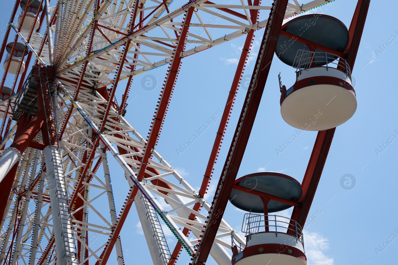 Photo of Beautiful Ferris wheel against blue sky on sunny day, low angle view