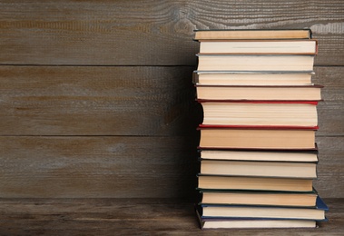 Stack of hardcover books on wooden background. Space for text