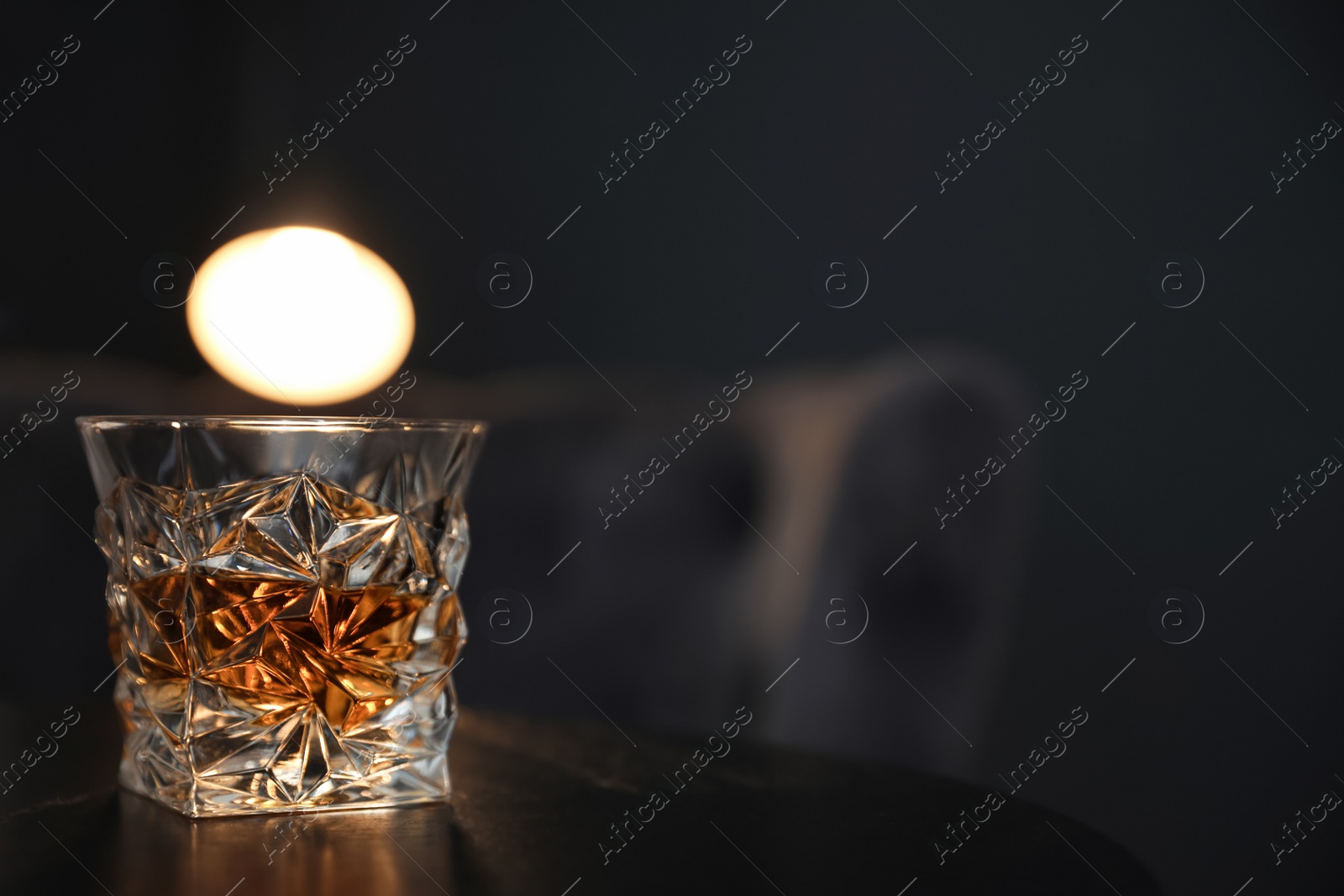 Photo of Glass of whiskey on table against dark background. Space for text