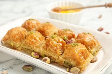 Photo of Delicious baklava with pistachios and scattered nuts on white marble table, closeup