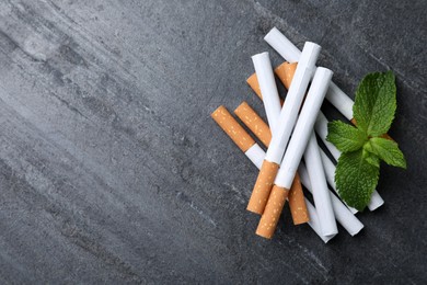 Photo of Menthol cigarettes and mint on grey table, flat lay. Space for text
