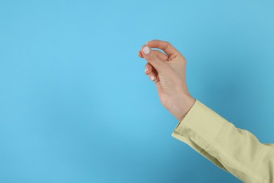 Photo of Woman snapping fingers on light blue background, closeup of hand. Space for text