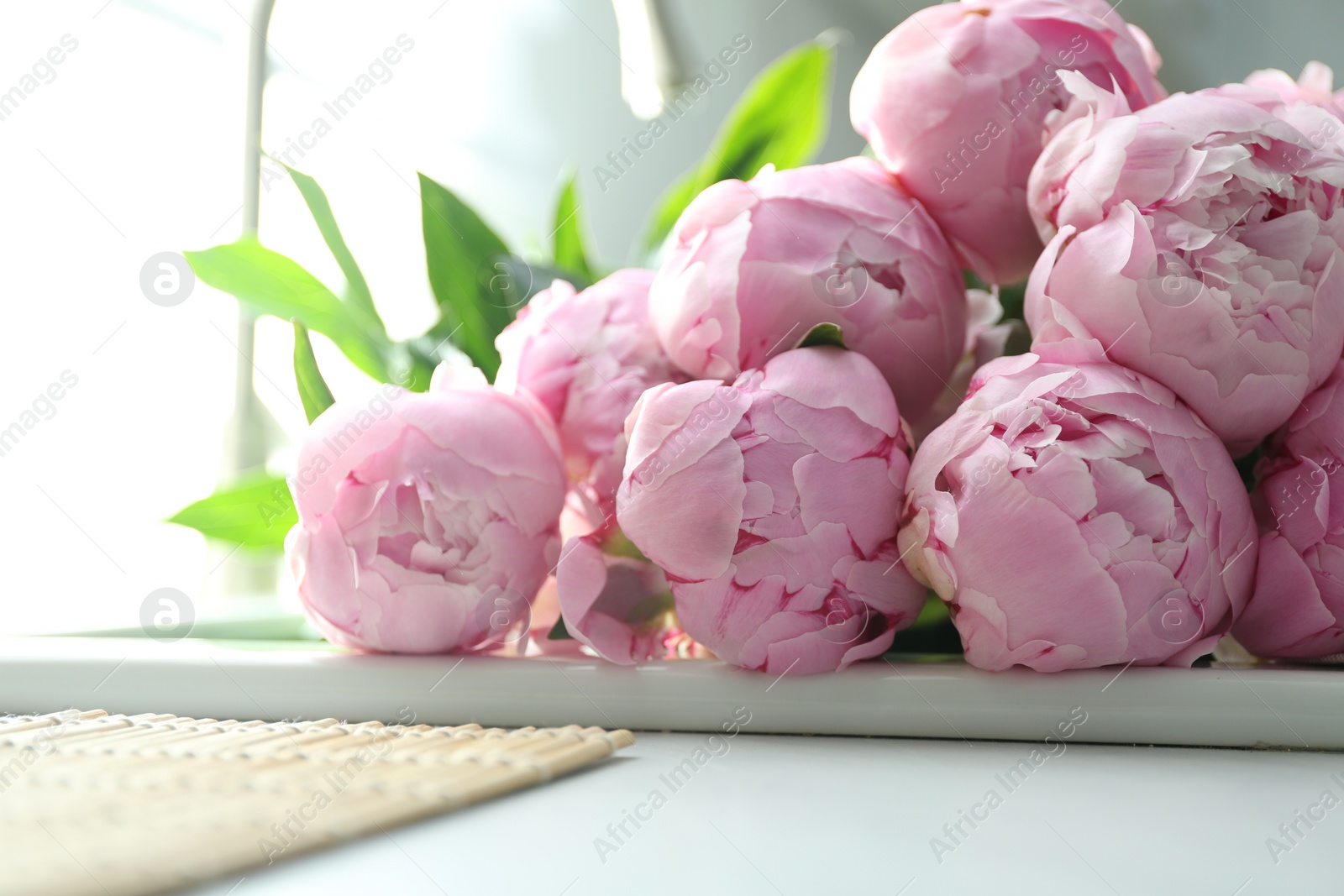 Photo of Bouquet of beautiful pink peonies in kitchen sink