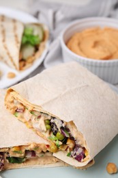 Photo of Delicious hummus wraps with vegetables, closeup view