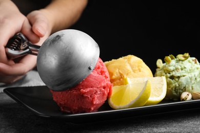 Woman putting strawberry ice cream scoop onto plate, closeup