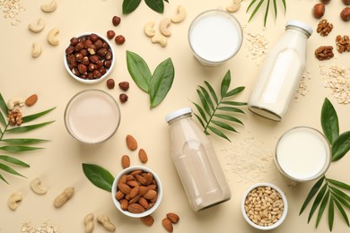 Different vegan milks and ingredients on beige background, flat lay