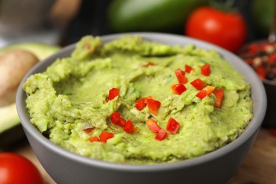 Photo of Bowl of delicious guacamole on table, closeup