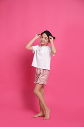 Photo of Cute girl in pajamas with sleep mask on pink background