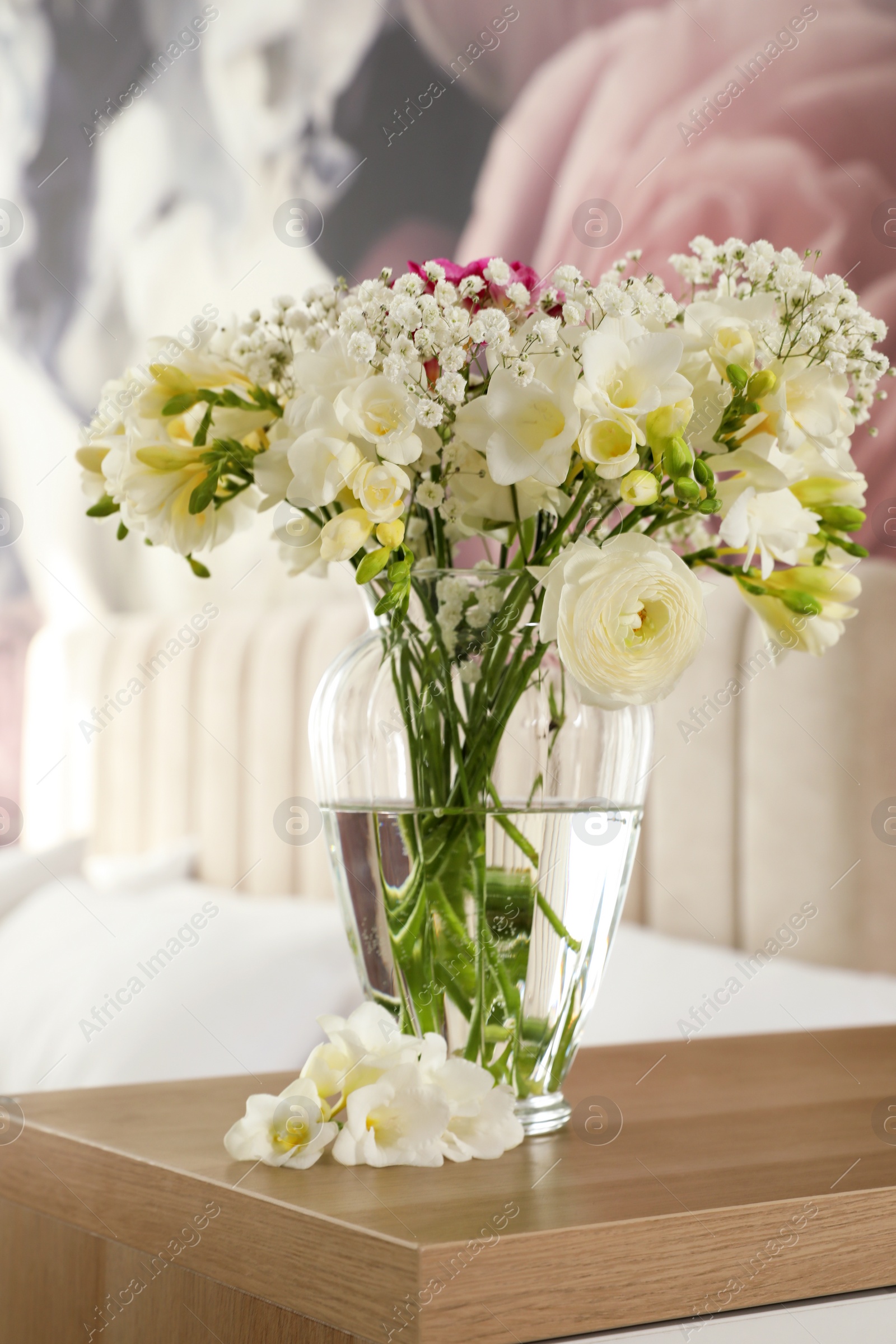 Photo of Beautiful bouquet with fresh freesia flowers on table in bedroom