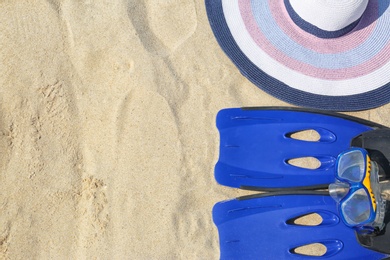 Flat lay composition with beach accessories on sand. Space for text