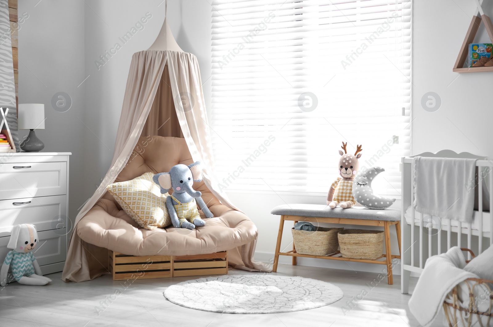 Photo of Beautiful baby room interior with comfortable armchair and bench near window