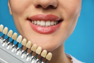 Photo of Woman checking her teeth color on blue background, closeup. Cosmetic dentistry