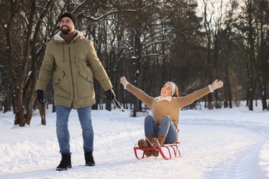 Photo of Man pulling his girlfriend in sleigh outdoors on winter day