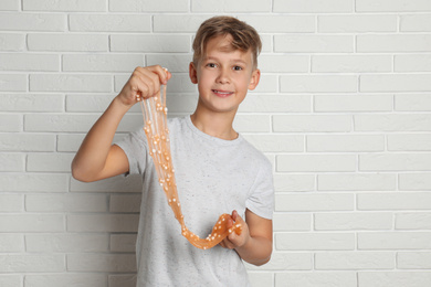 Preteen boy with slime near white brick wall