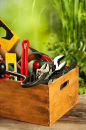 Photo of Crate with different tools on wooden table outdoors