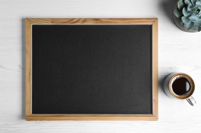 Photo of Clean small chalkboard, coffee and plant on white wooden table, flat lay