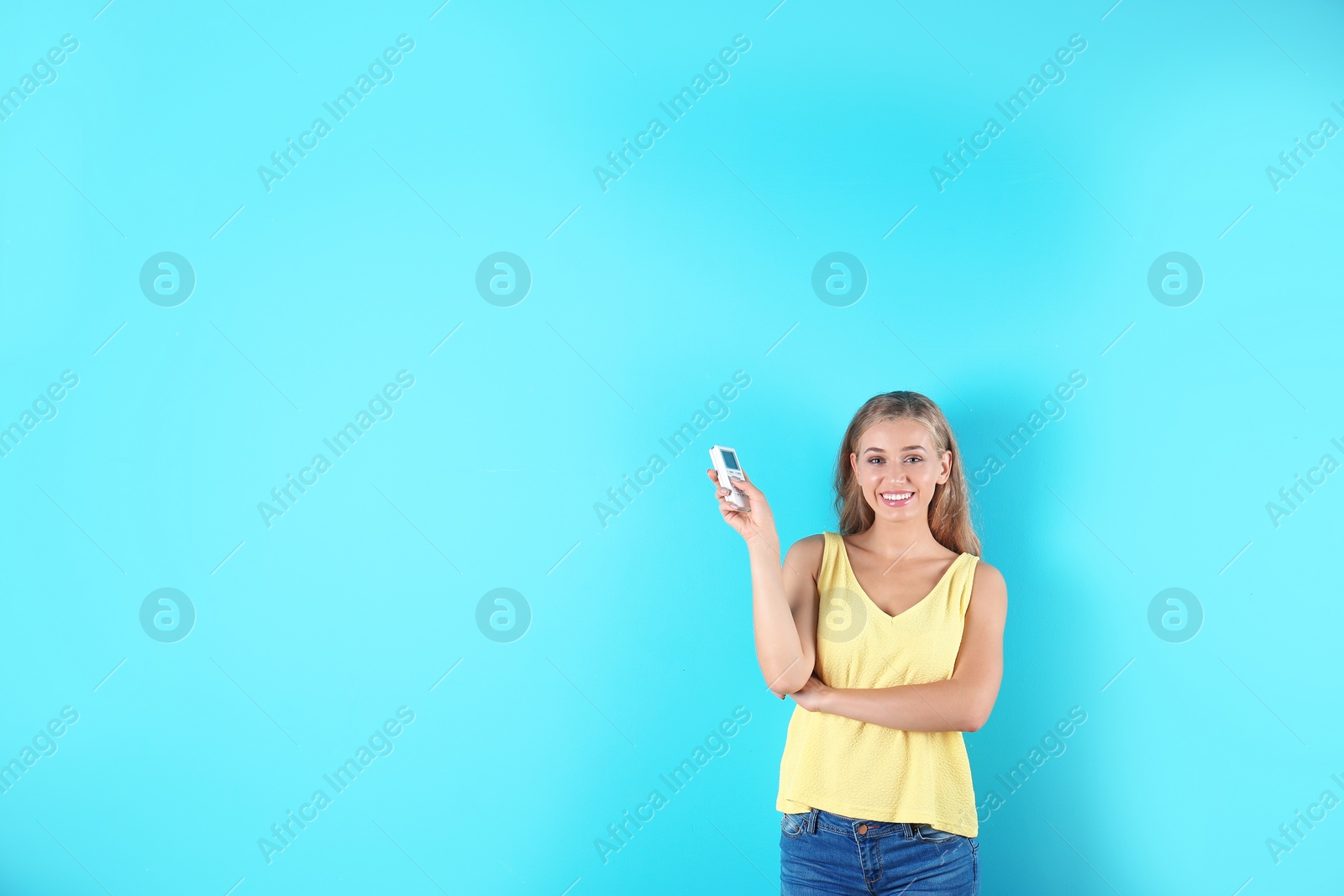 Photo of Young woman with air conditioner remote on color background, copy space text