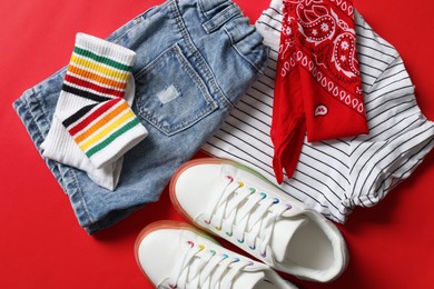 Photo of Stylish child clothes, shoes and accessories on red background, flat lay