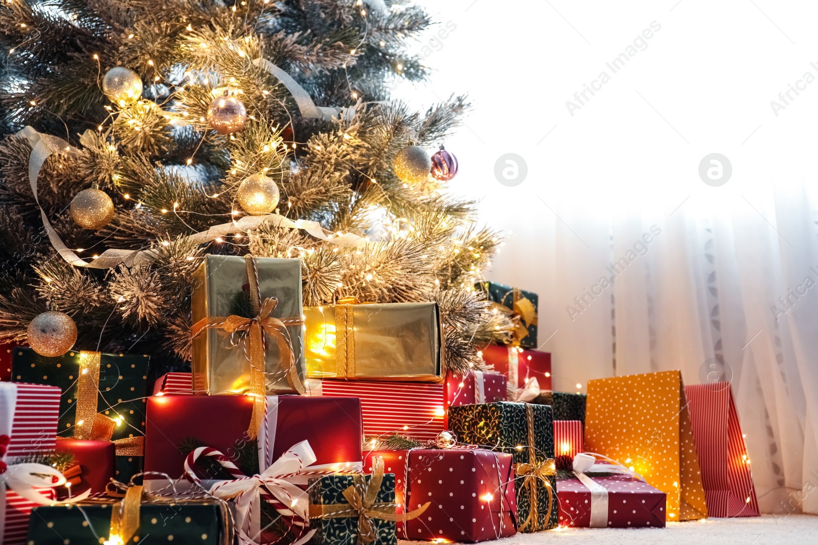 Photo of Many different gifts under Christmas tree indoors