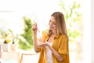 Photo of Young attractive woman eating tasty yogurt, indoors