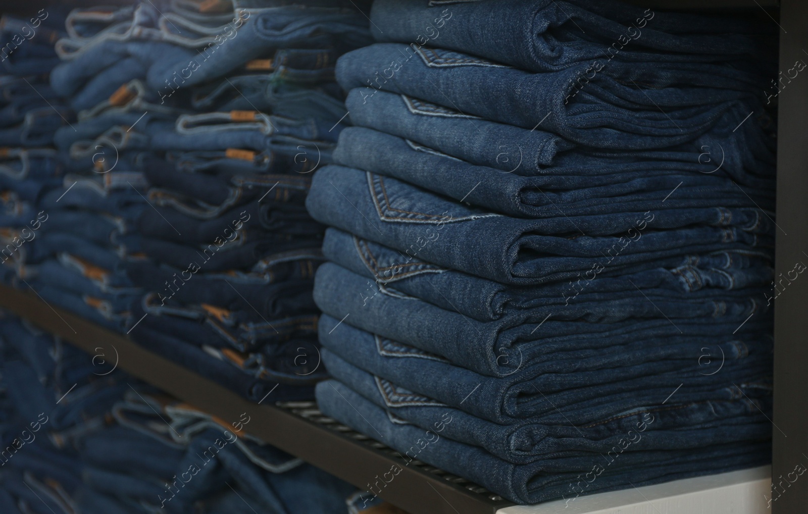 Photo of Collection of stylish jeans on shelves in shop