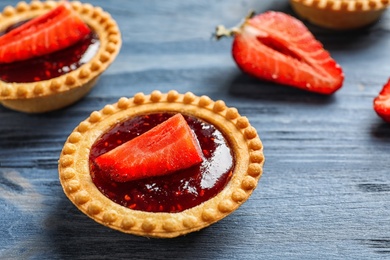 Tasty tartlets with strawberry jam on wooden background