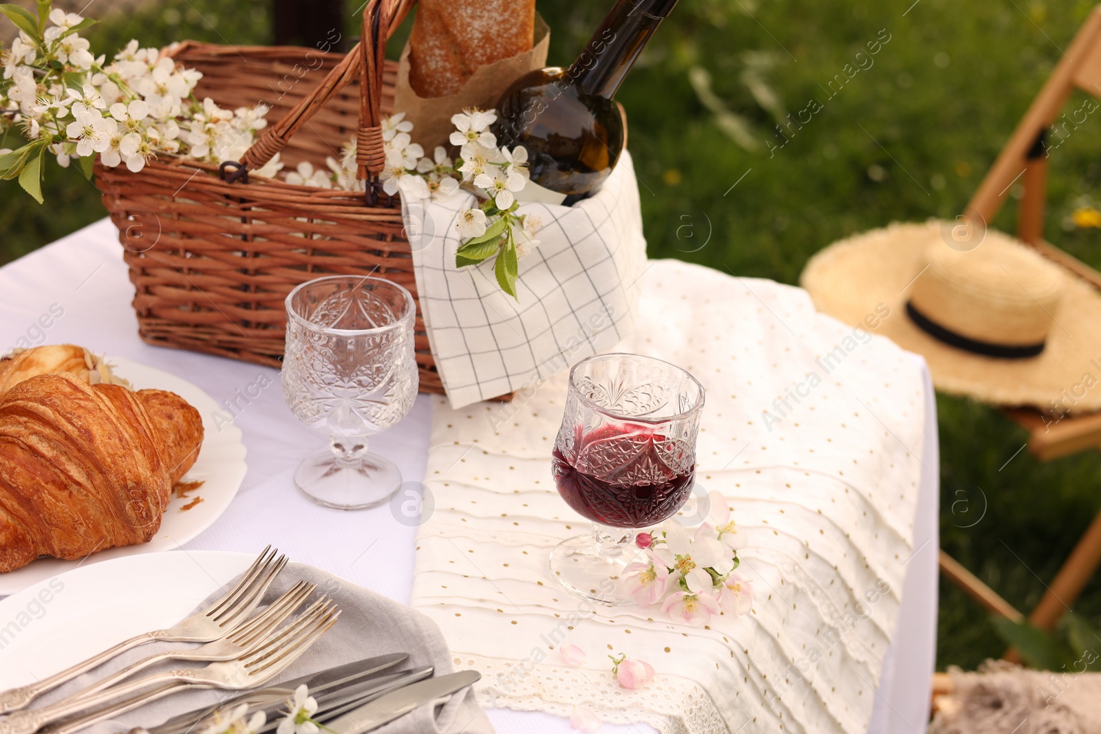 Photo of Stylish table setting with beautiful spring flowers, wine and croissants in garden