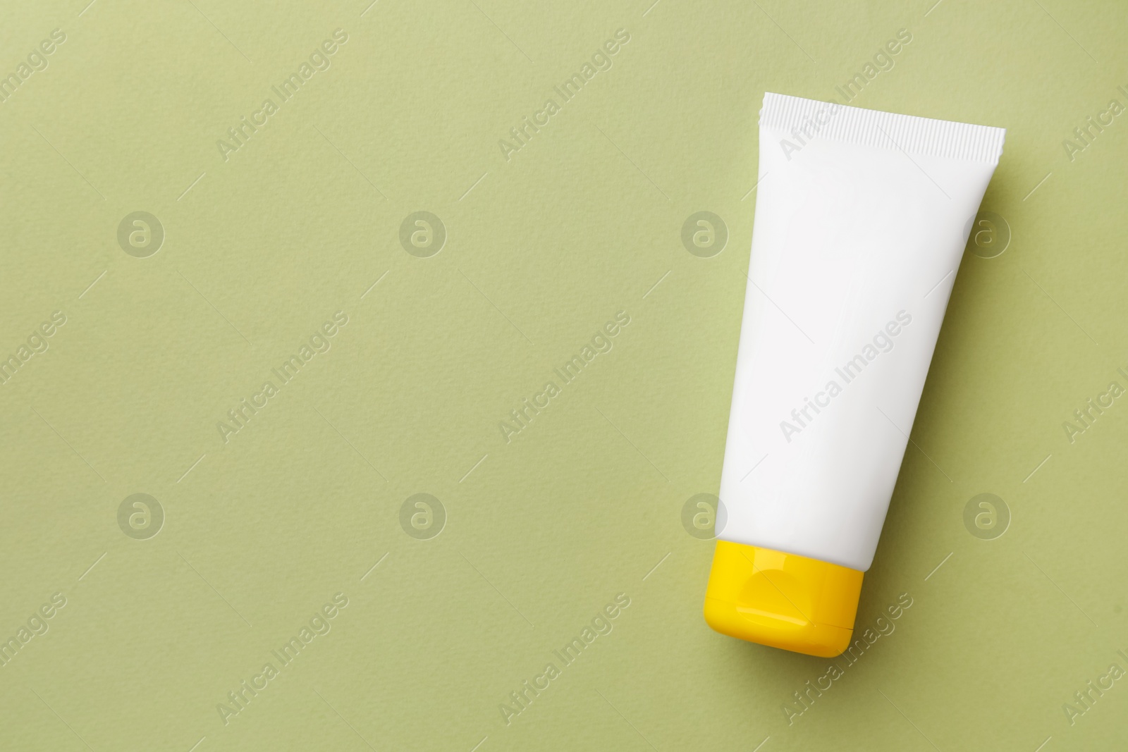 Photo of Tube of face cream on light green background, top view. Space for text