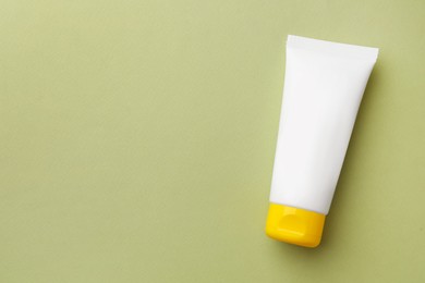Photo of Tube of face cream on light green background, top view. Space for text