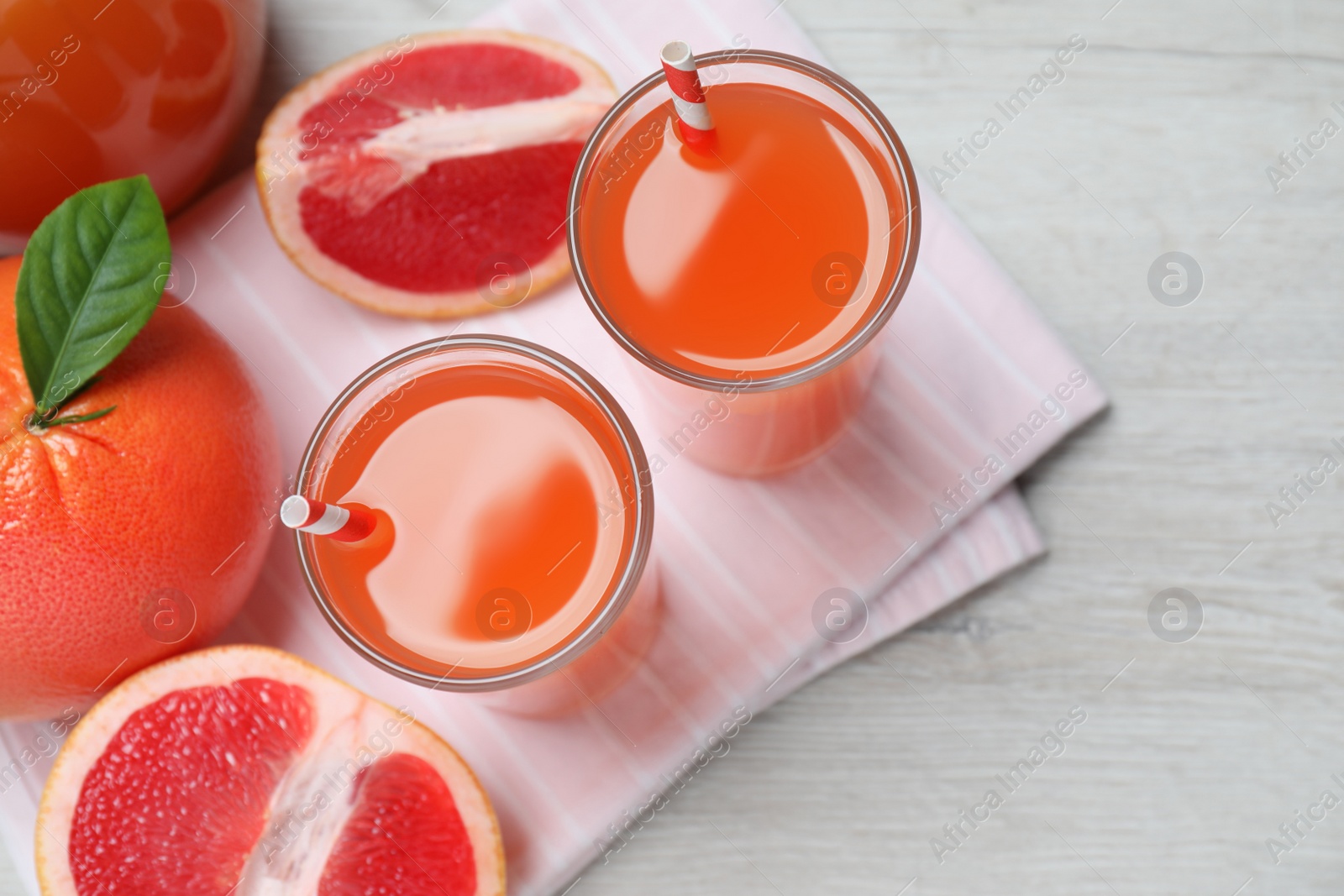 Photo of Tasty freshly made grapefruit juice and fruits on white wooden table, flat lay