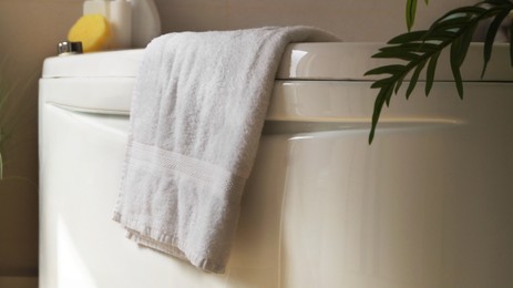 Photo of Soft fluffy towel hanging on bathtub indoors