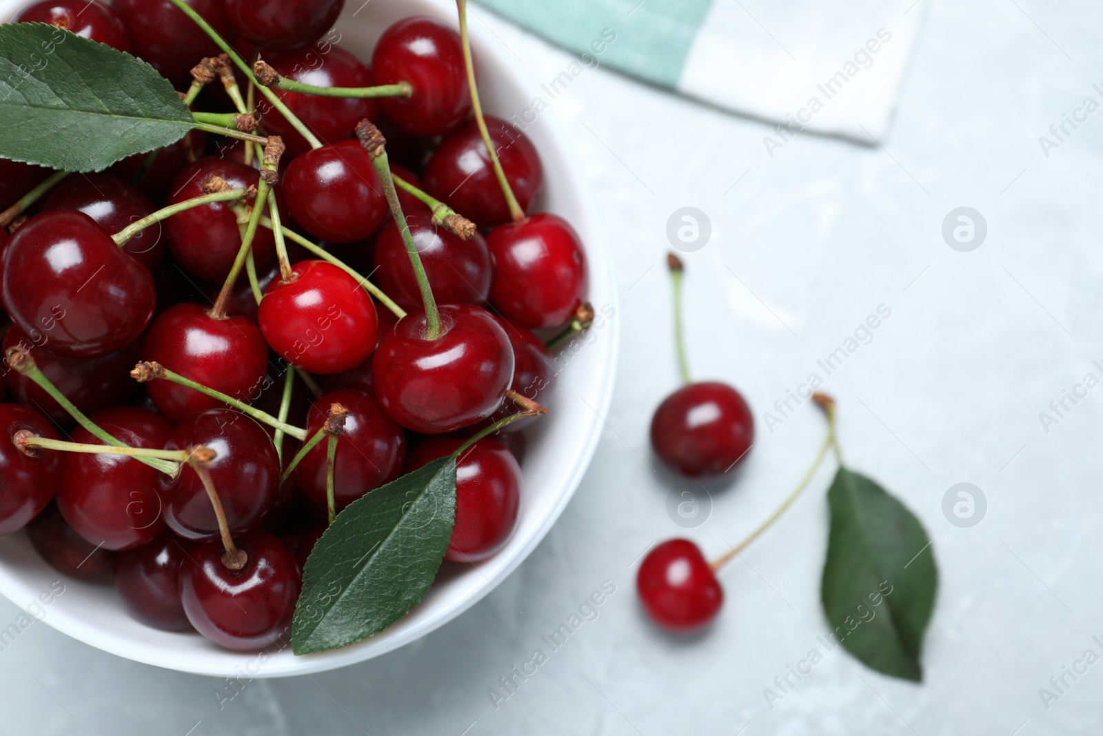 Photo of Sweet juicy cherries with leaves on grey marble table, top view