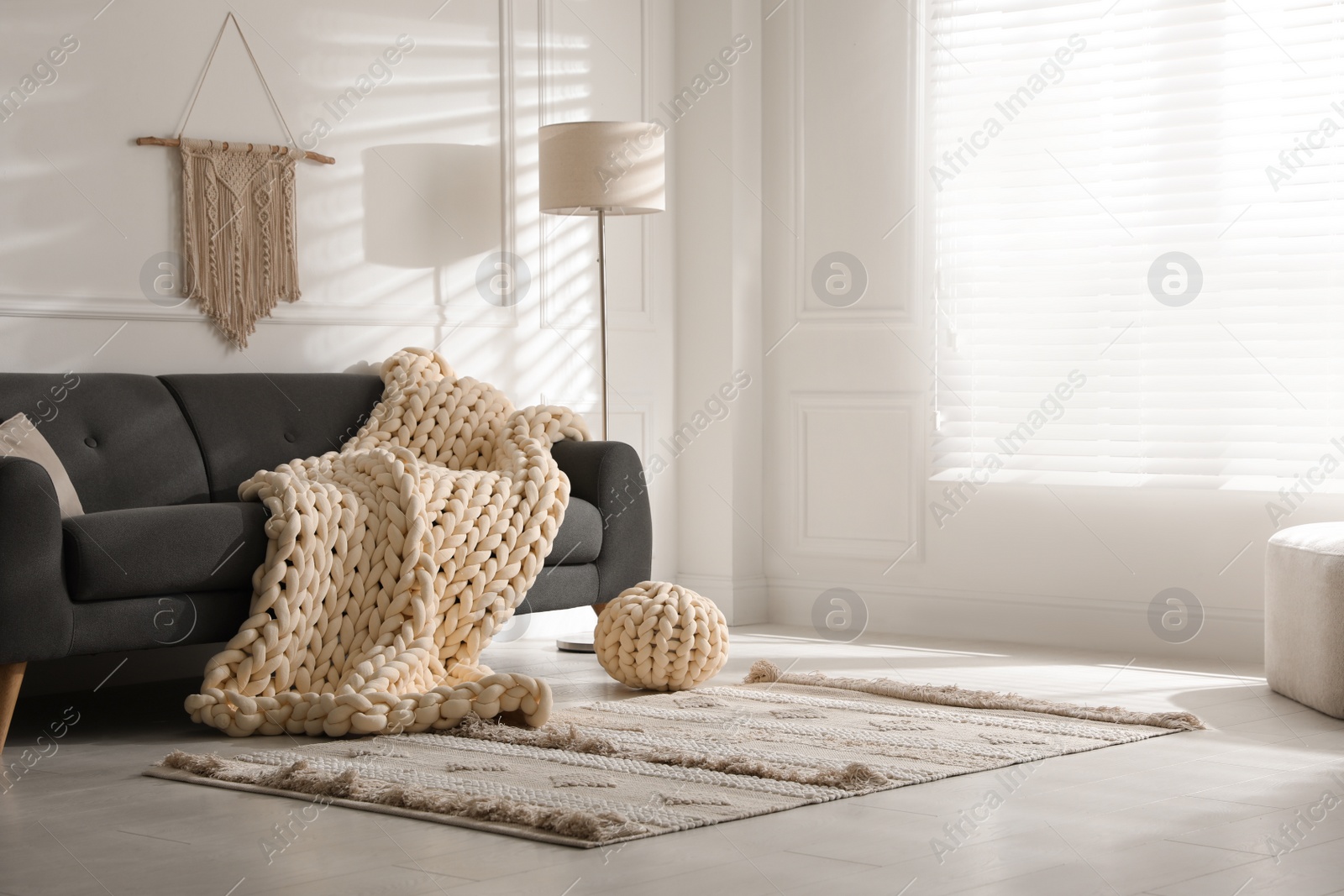 Photo of Soft chunky knit blanket on sofa in living room. Interior design