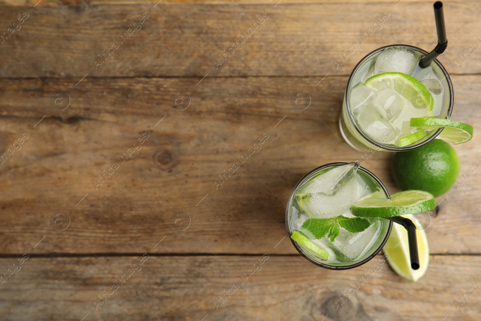 Photo of Delicious mojito and ingredients on wooden table, flat lay. Space for text