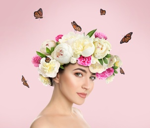 Pretty woman wearing beautiful wreath made of flowers on light pink background