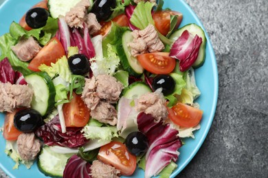 Photo of Plate of delicious salad with canned tuna and vegetables on grey table, top view