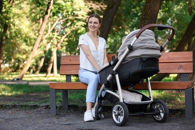 Happy nanny with baby in stroller in park