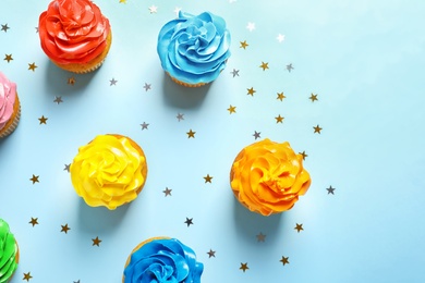 Photo of Flat lay composition with colorful birthday cupcakes on color background