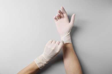 Doctor wearing white medical gloves on grey background, top view