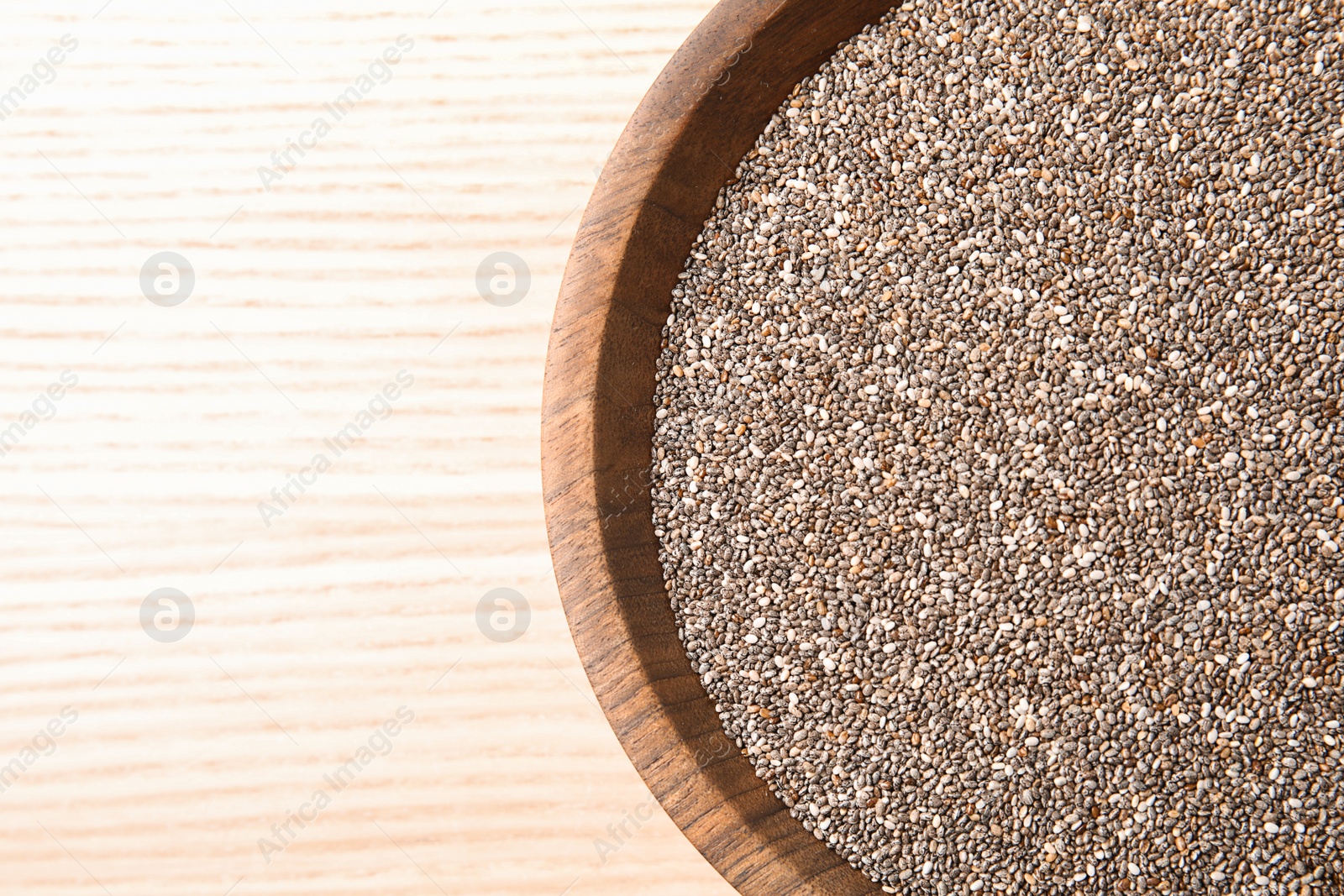 Photo of Bowl with chia seeds on wooden background, top view. Space for text