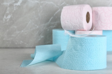 Photo of Roll of toilet paper with feather on grey table. Space for text