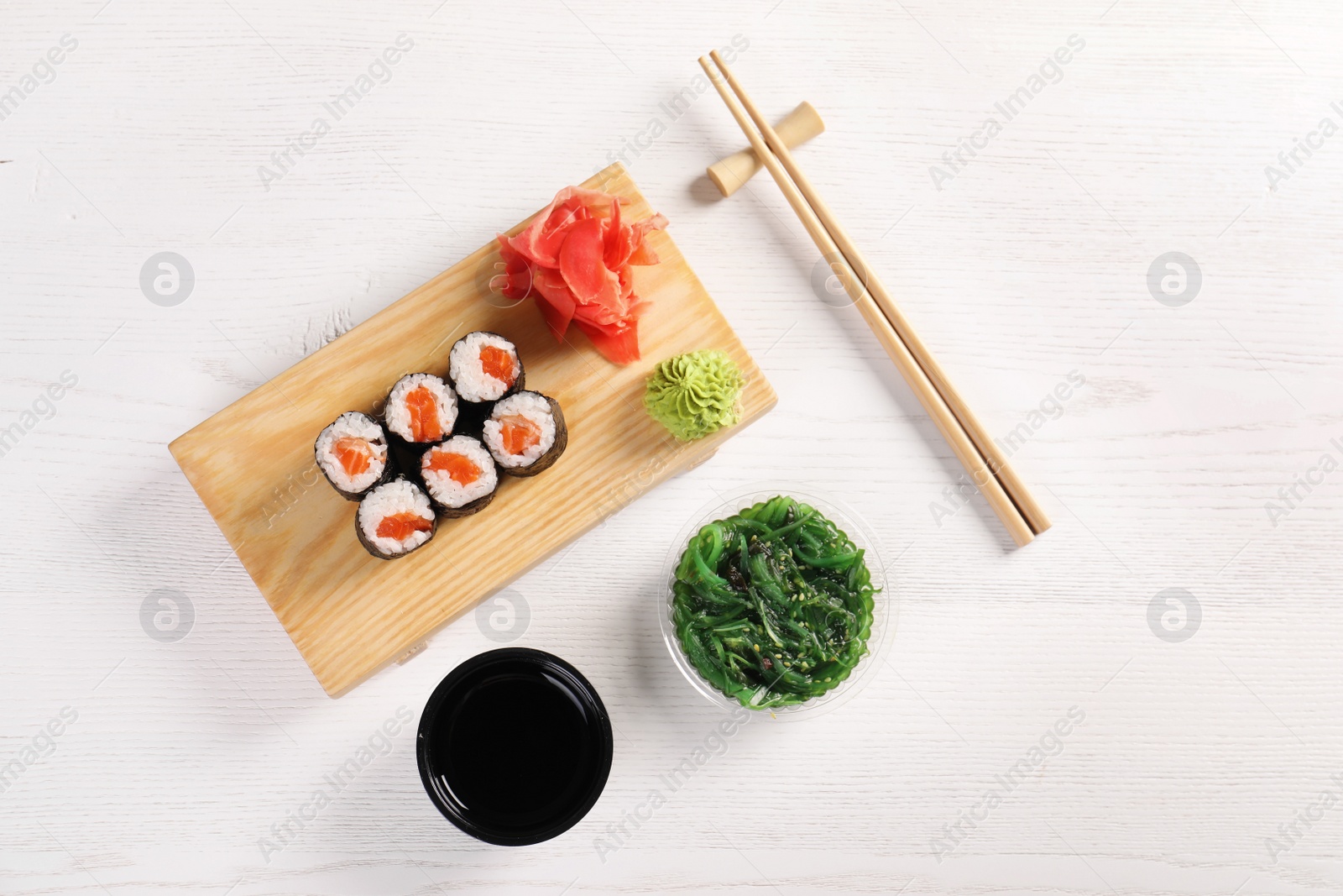 Photo of Flat lay composition with sushi rolls on white wooden table. Food delivery