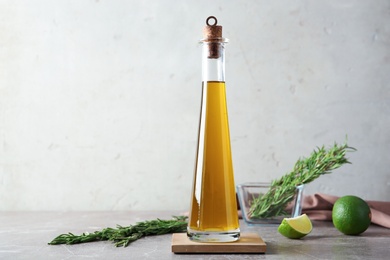 Photo of Bottle with fresh rosemary oil on table