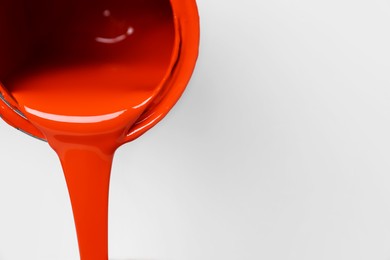 Photo of Pouring orange paint from can on white background, closeup. Space for text