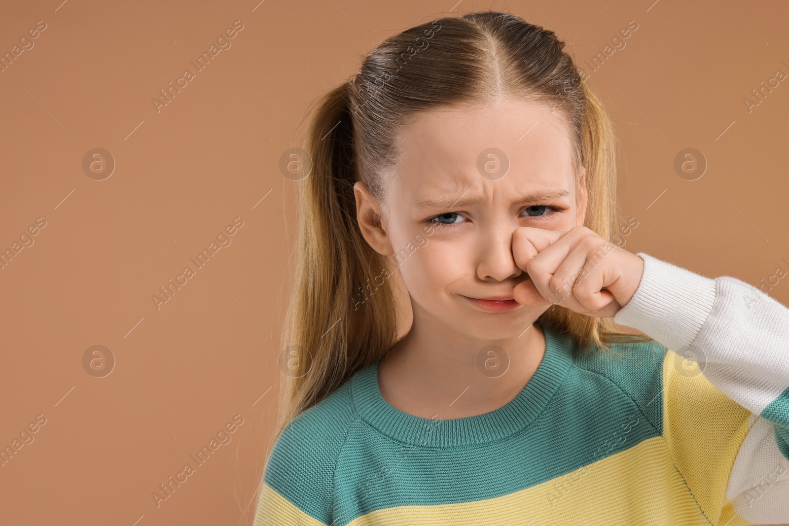 Photo of Portrait of sad girl on light brown background, space for text