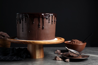 Photo of Freshly made delicious chocolate cake on grey table against black background