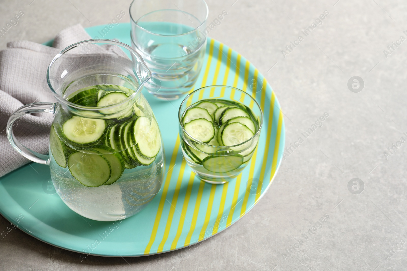 Photo of Glasses and jug of fresh cucumber water on table. Space for text