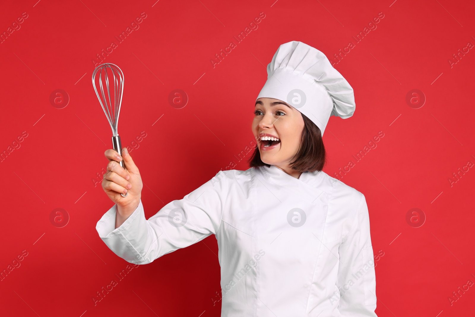 Photo of Happy confectioner holding whisk on red background