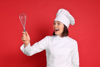 Happy confectioner holding whisk on red background